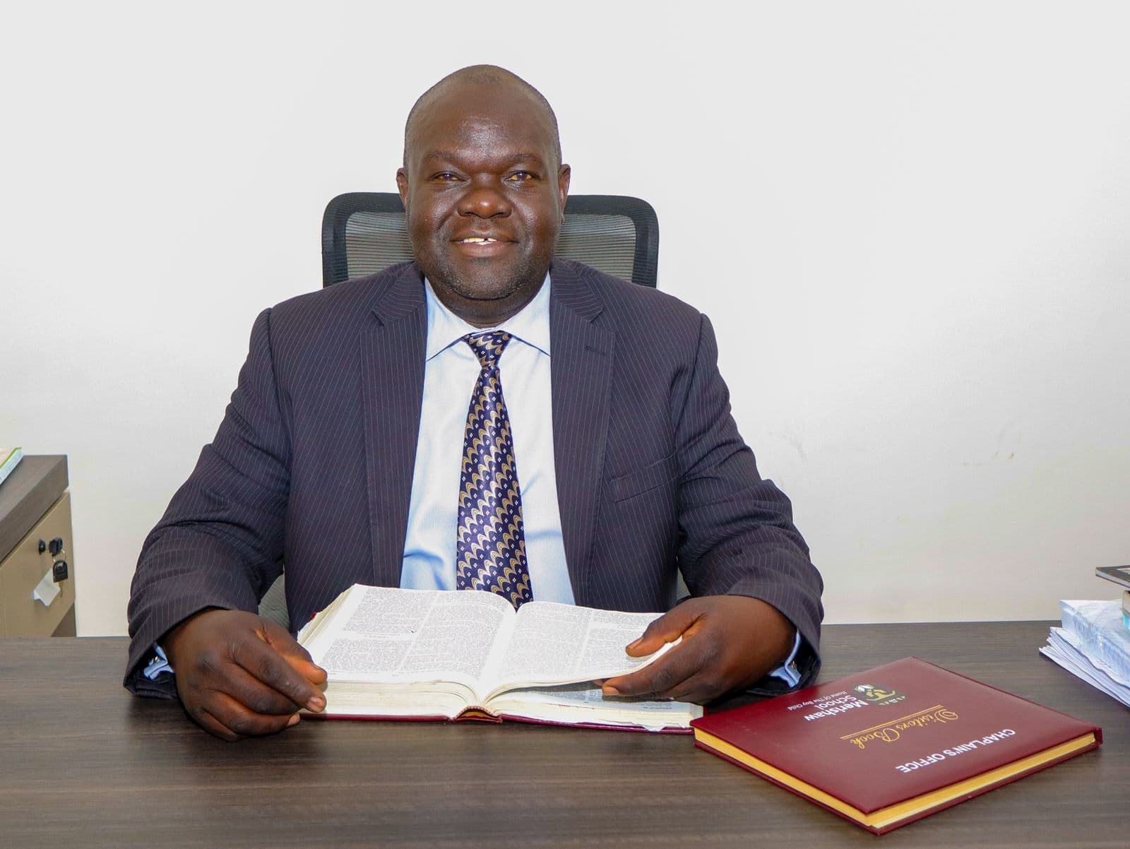 Merishaw School chaplain seated at a desk with an open Bible